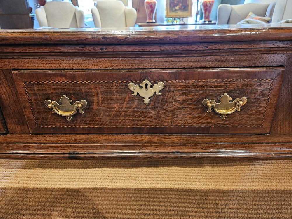 A mid-18th century George II dark oak dresser base featuring three drawers with brass swan-neck handles, raised on slender cabriole legs with pad feet. View V