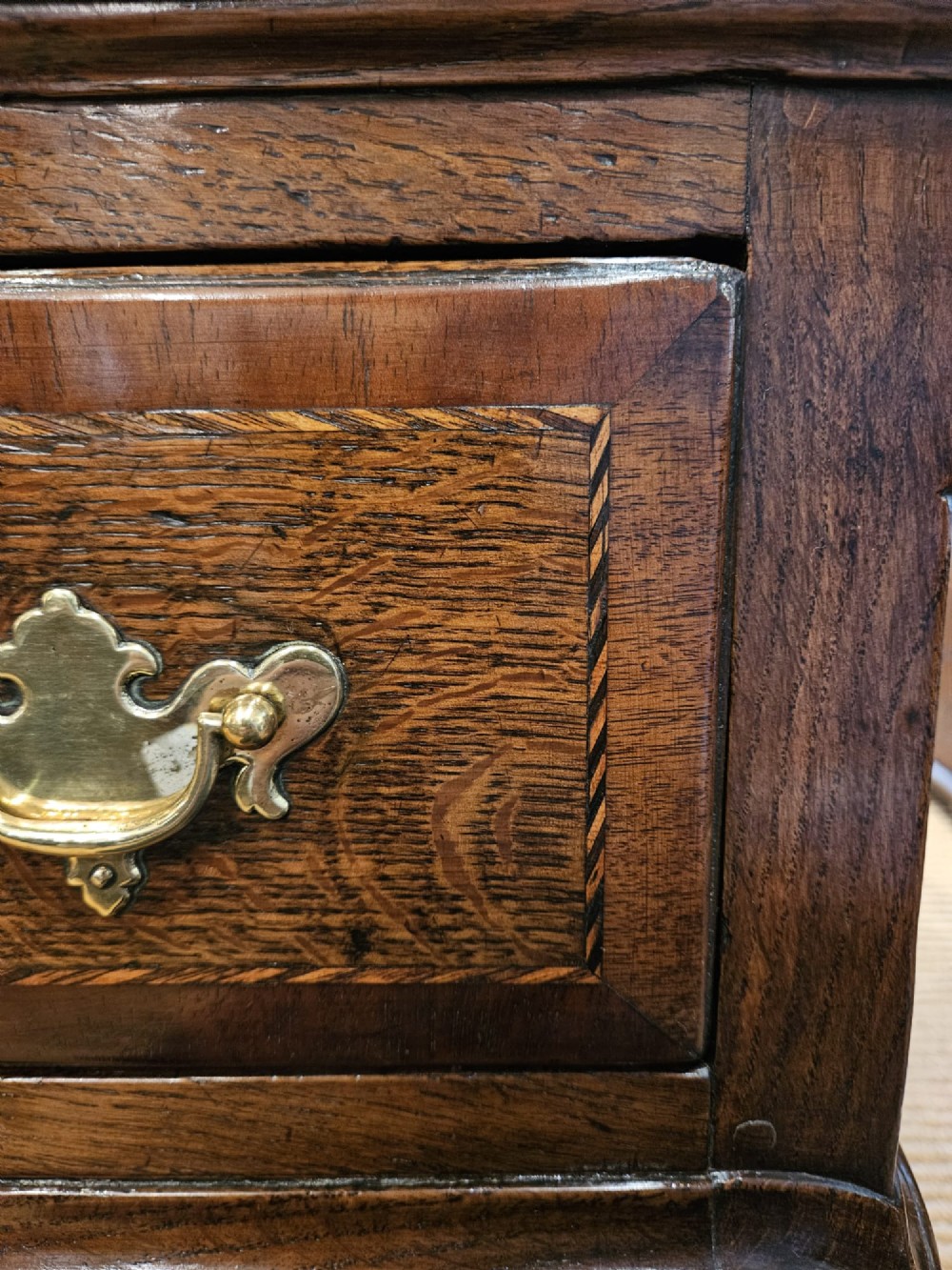 A mid-18th century George II dark oak dresser base featuring three drawers with brass swan-neck handles, raised on slender cabriole legs with pad feet. View VII