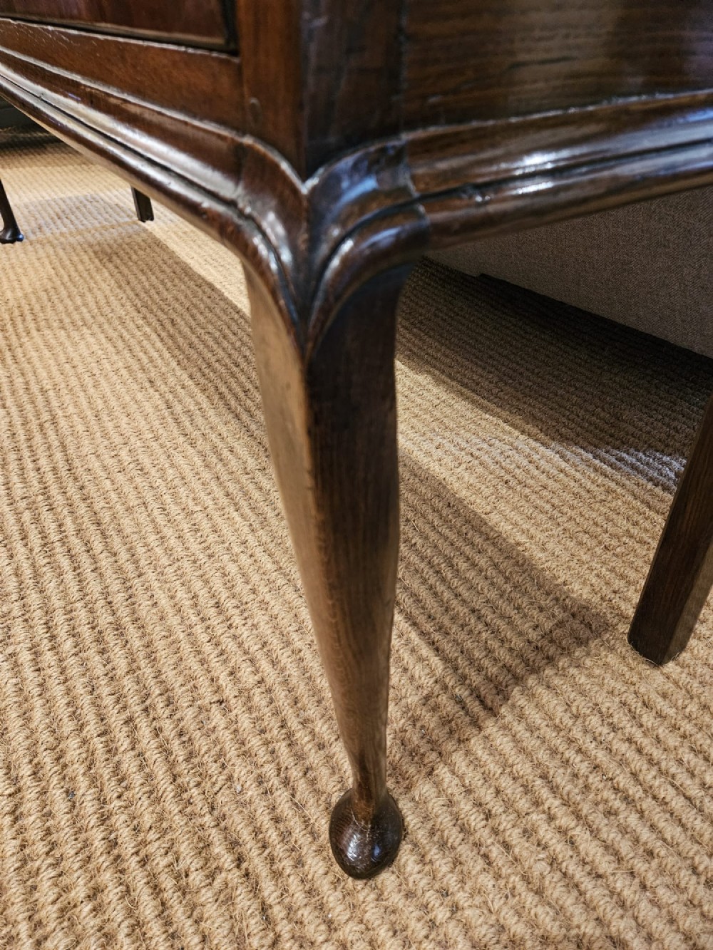 A mid-18th century George II dark oak dresser base featuring three drawers with brass swan-neck handles, raised on slender cabriole legs with pad feet. View VIII