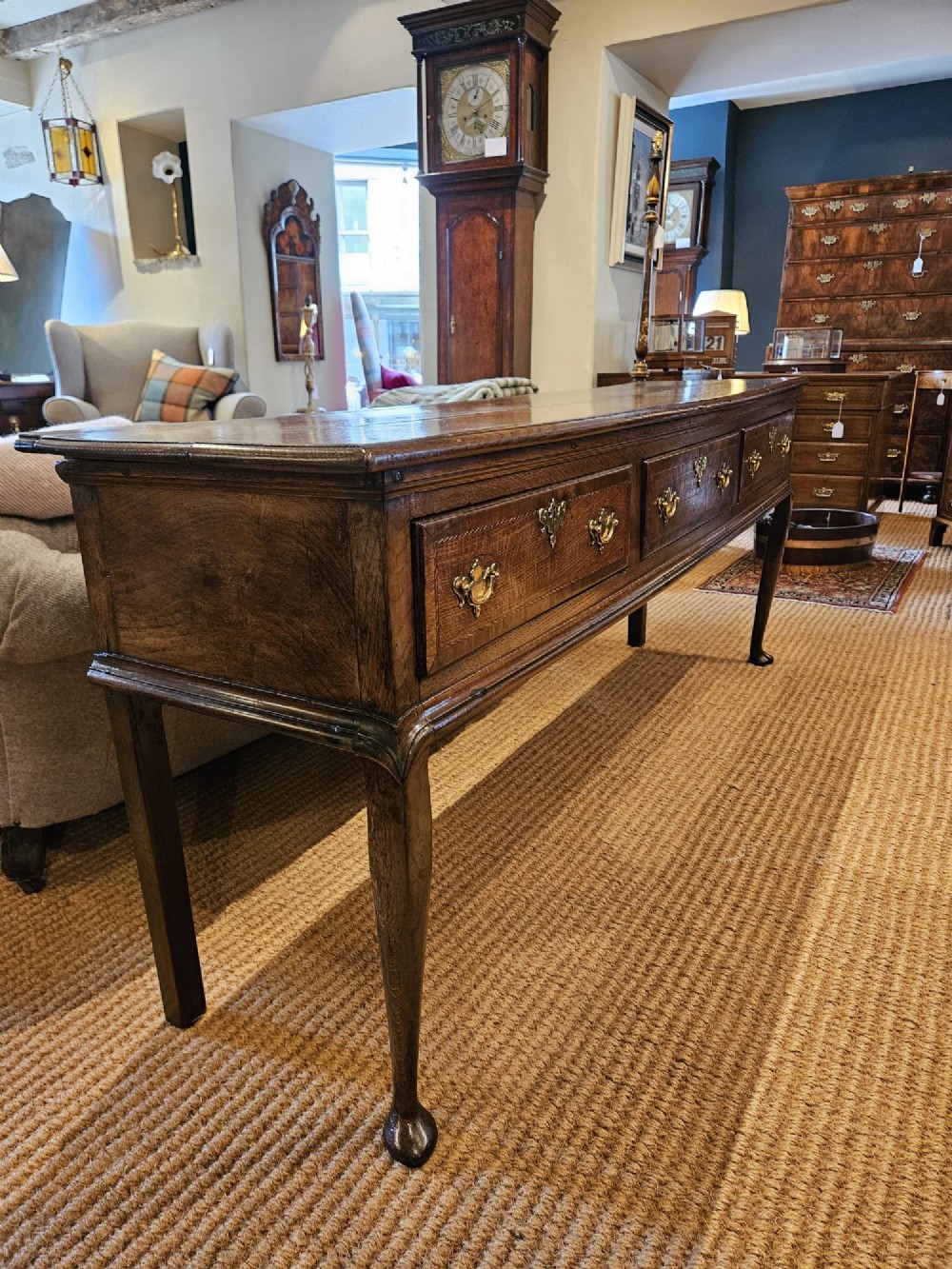 A mid-18th century George II dark oak dresser base featuring three drawers with brass swan-neck handles, raised on slender cabriole legs with pad feet. View X