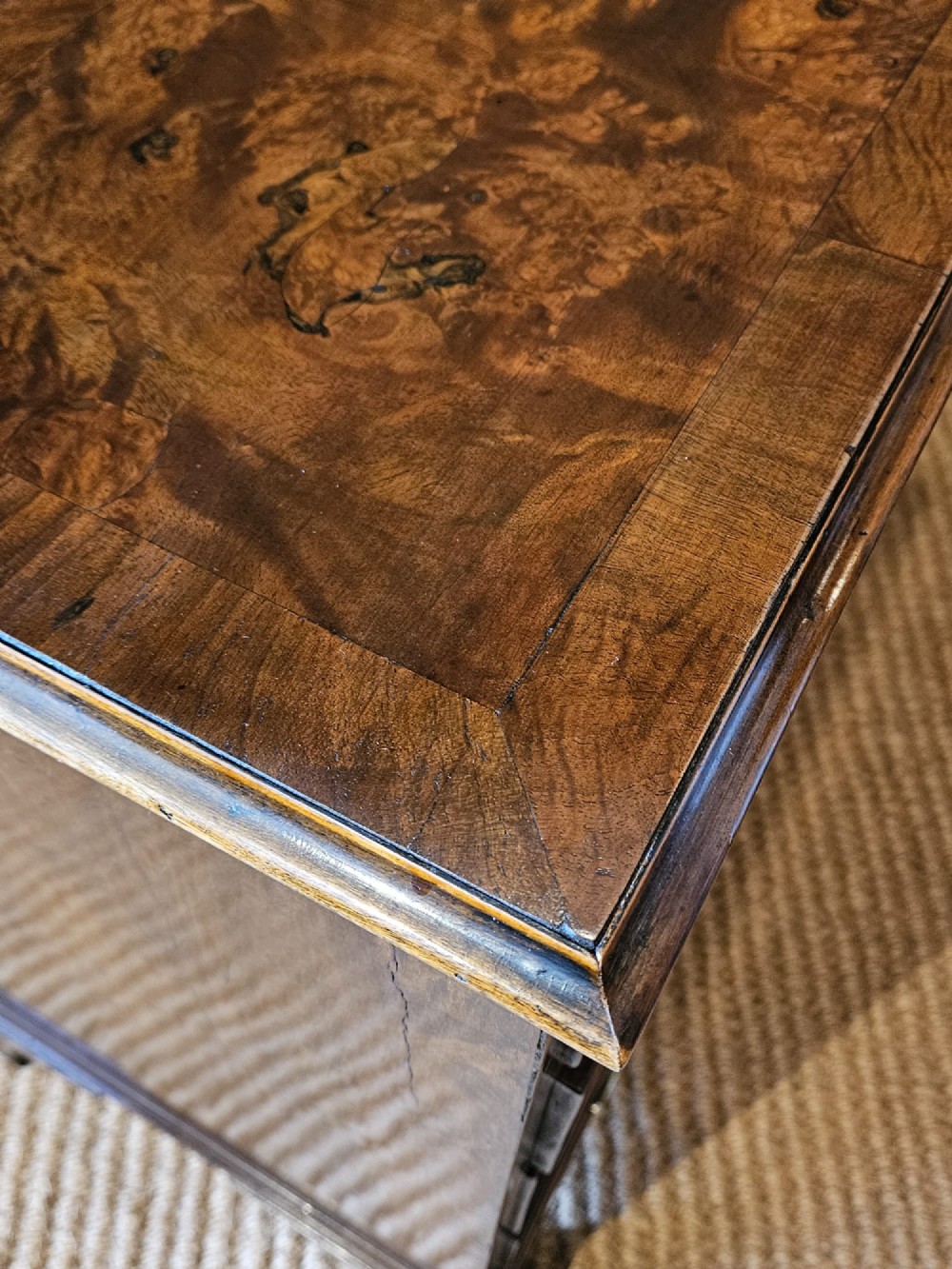 A small George III walnut chest of drawers featuring four graduated drawers with brass handles, keyhole escutcheons, and bracket feet against a dark grey background. View VII