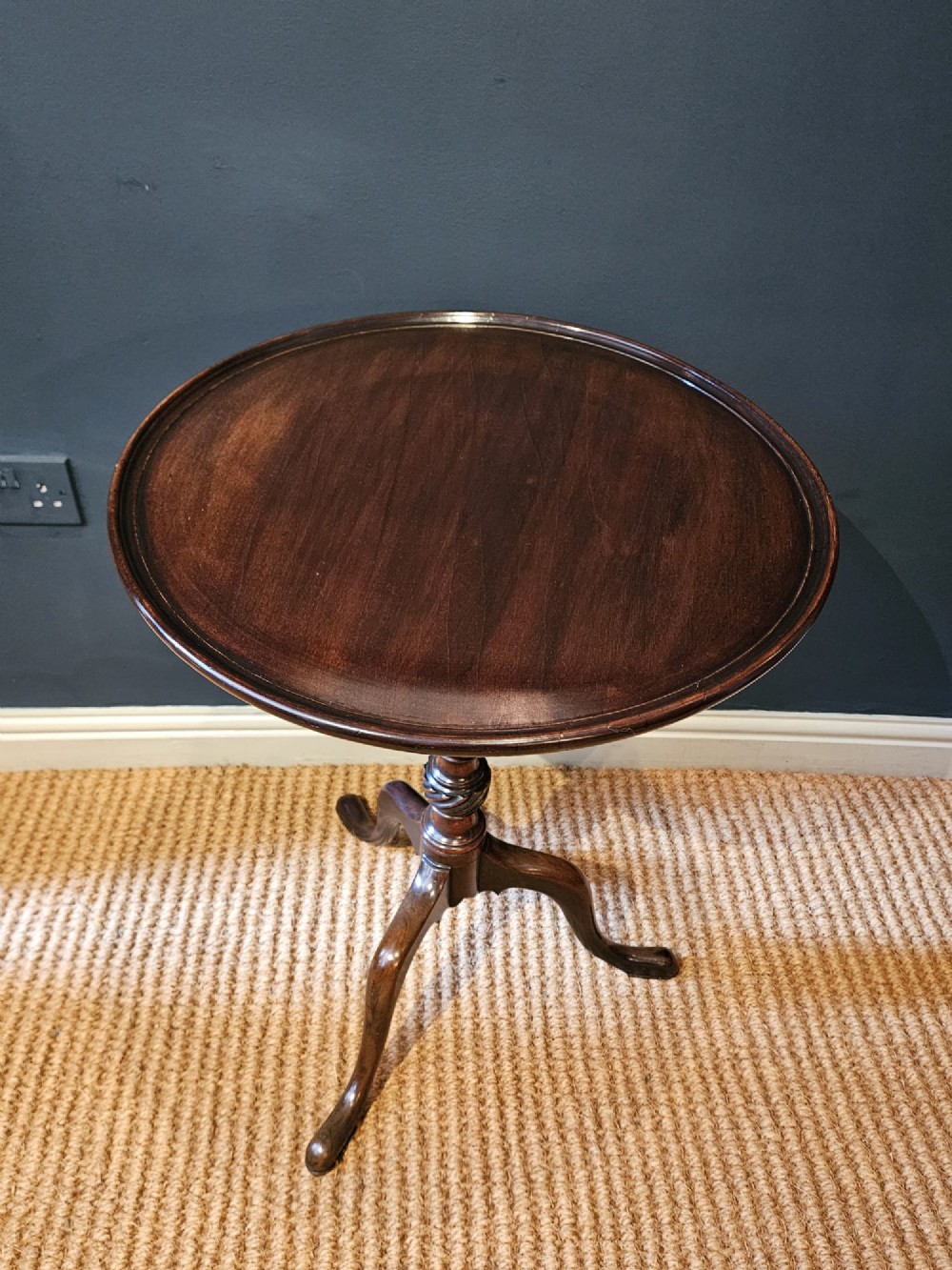 A George III mahogany snap top tripod table featuring a circular dished top, turned column with spiral detailing, and splayed cabriole legs. View II