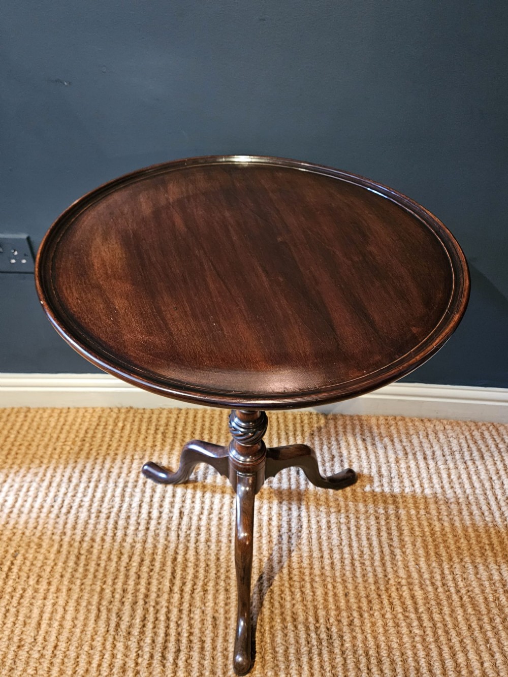 A George III mahogany snap top tripod table featuring a circular dished top, turned column with spiral detailing, and splayed cabriole legs. View V