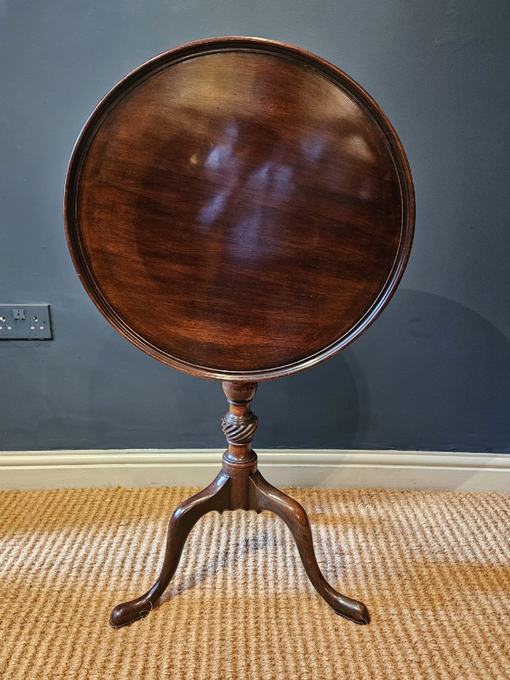 A George III mahogany snap top tripod table featuring a circular dished top, turned column with spiral detailing, and splayed cabriole legs. View VII