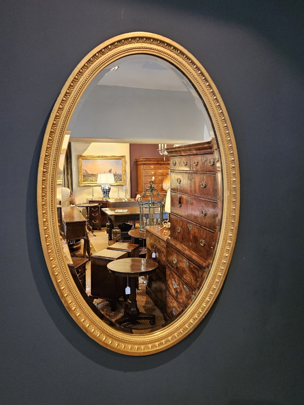 A vertical oval wall mirror featuring a gilded plaster frame decorated with egg and dart moulding details around the inner border. View II