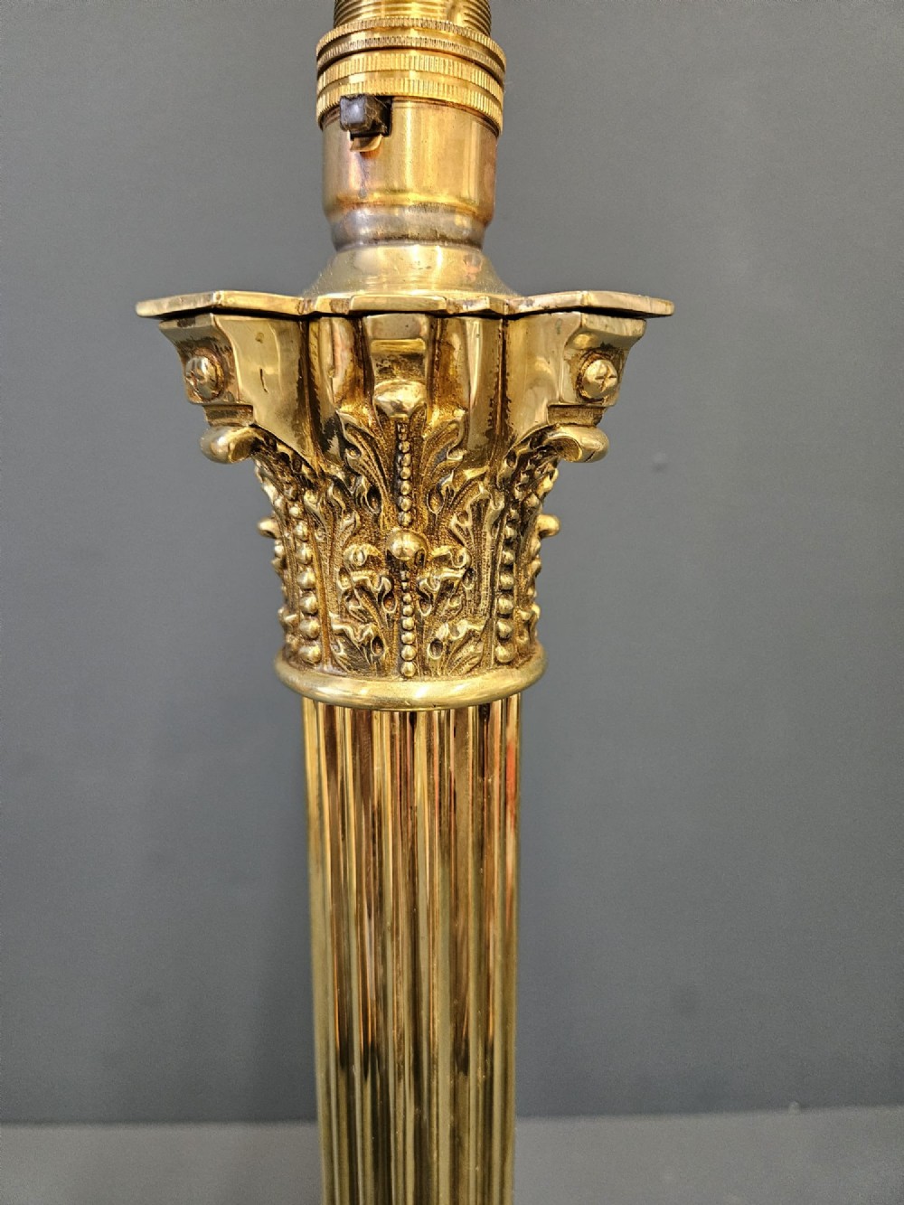 An antique brass table lamp designed as a fluted Corinthian column on a square stepped base with beaded detailing. View III