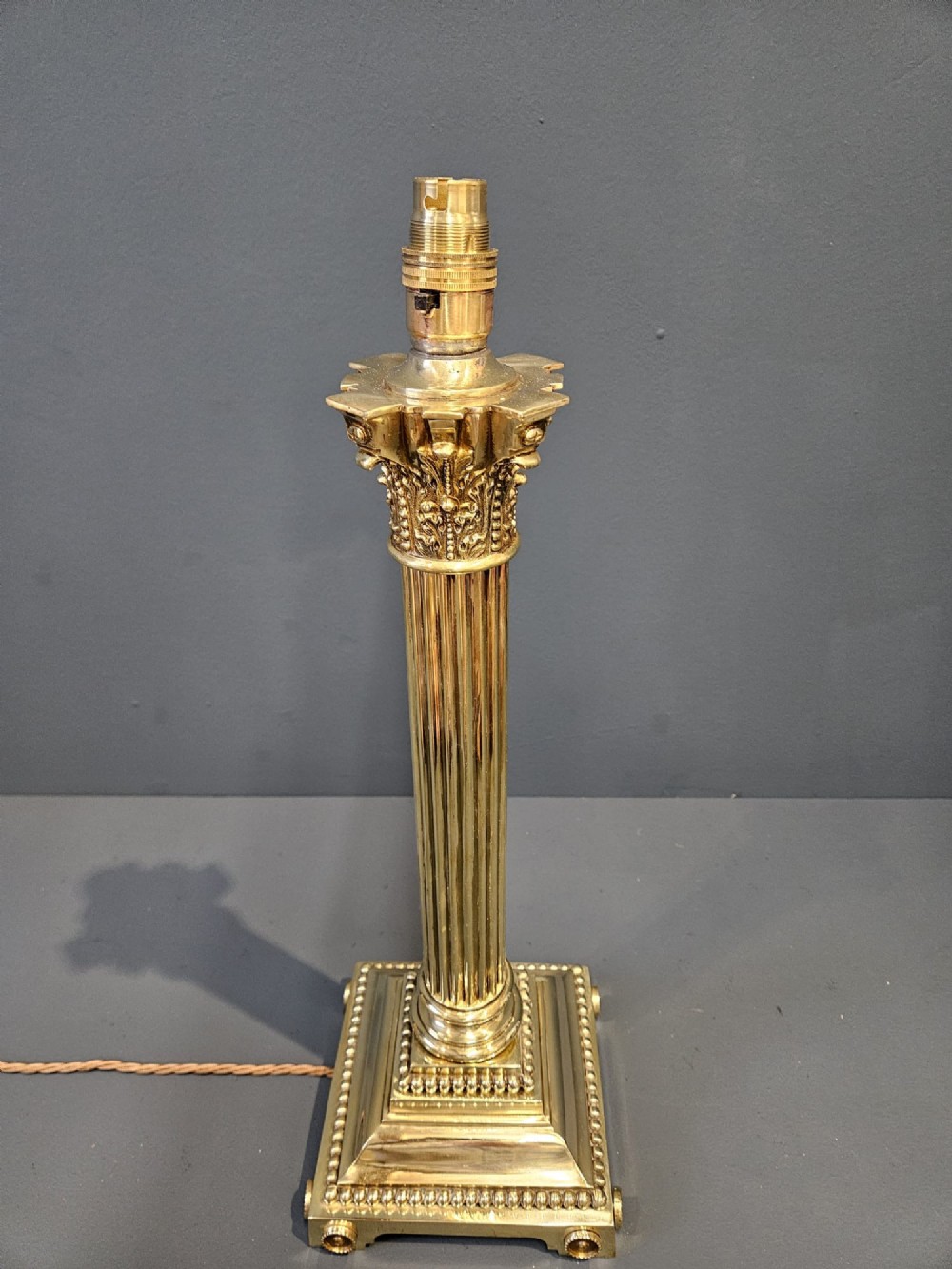 An antique brass table lamp designed as a fluted Corinthian column on a square stepped base with beaded detailing. View IV