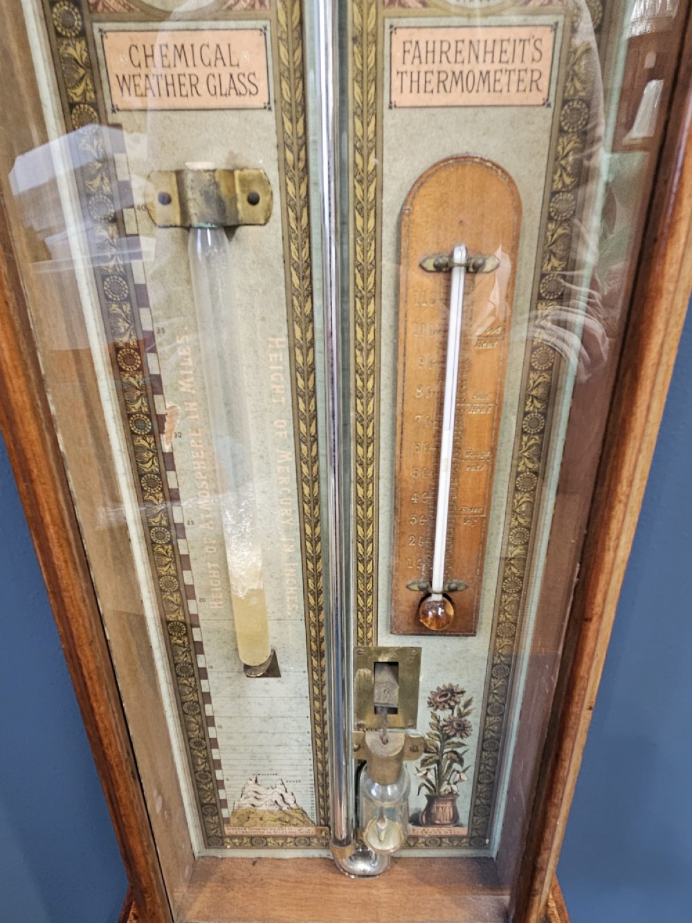 A glazed timber-cased Victorian Admiral Fitzroy wall barometer featuring printed weather prediction scales, a central glass barometer tube, a thermometer, and a storm glass. View II