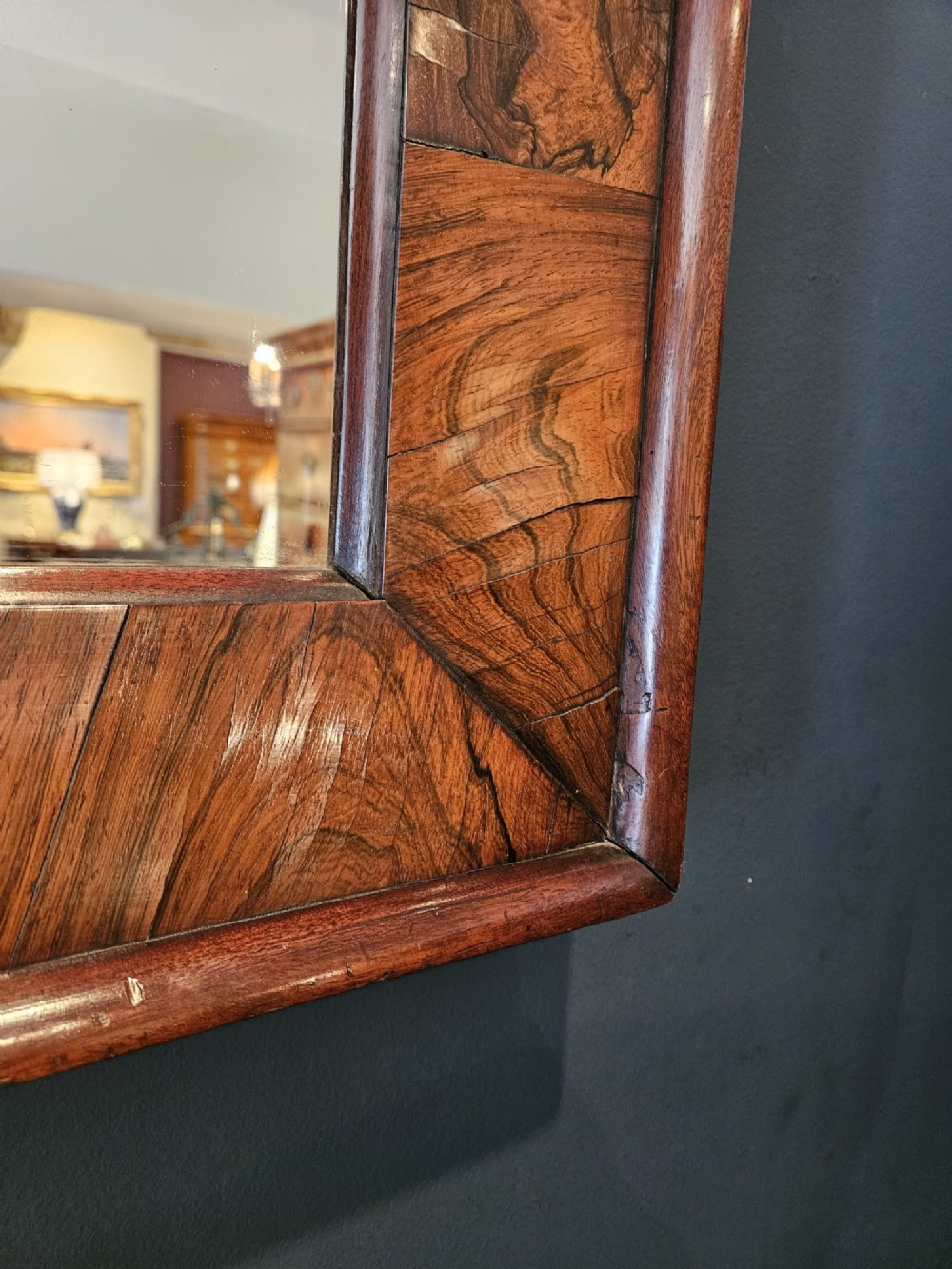 A rectangular wall mirror featuring a polished rosewood cushion frame with distinct wood grain patterns and mitred corner joints. View V