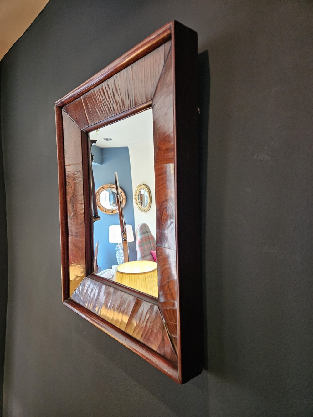 A rectangular wall mirror featuring a polished rosewood cushion frame with distinct wood grain patterns and mitred corner joints. View VI