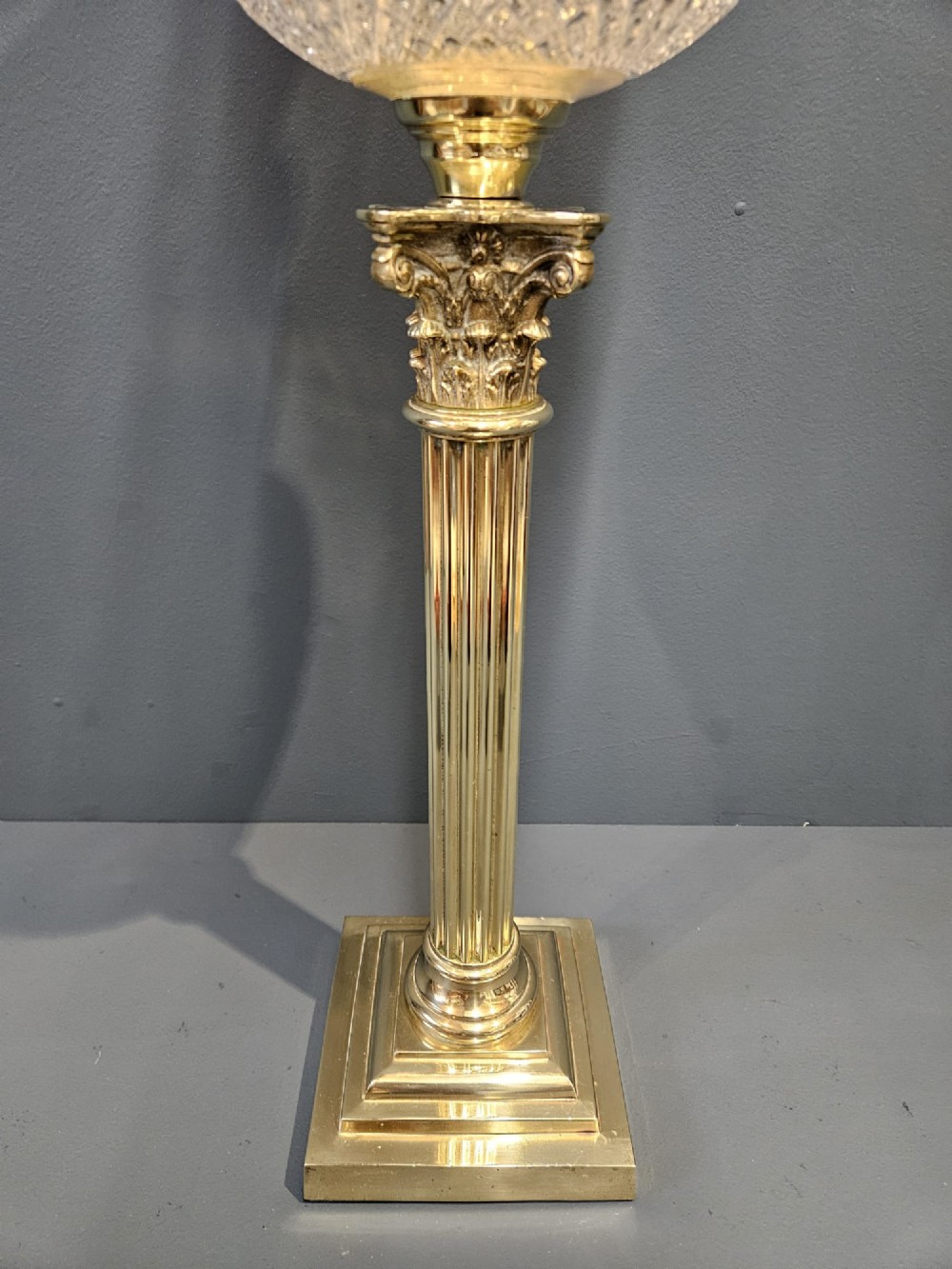 A Victorian oil lamp featuring a stepped brass base, fluted Corinthian column stem, cut crystal reservoir, etched pink glass shade, and clear glass chimney. View II