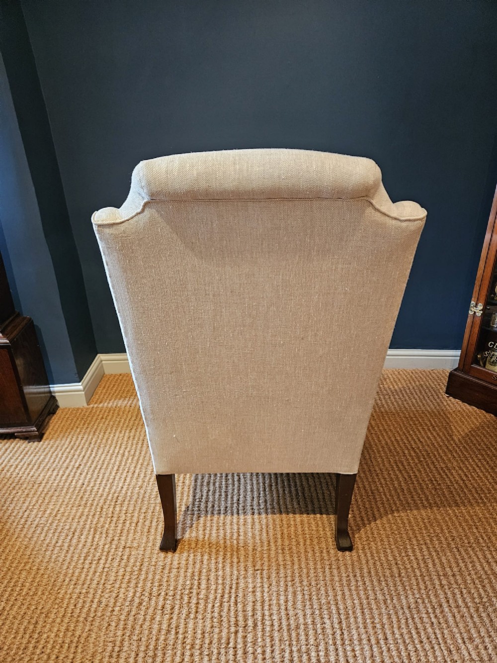 A pair of late Victorian wingback armchairs upholstered in natural oatmeal linen with dark carved cabriole legs and brass stud detailing. View II