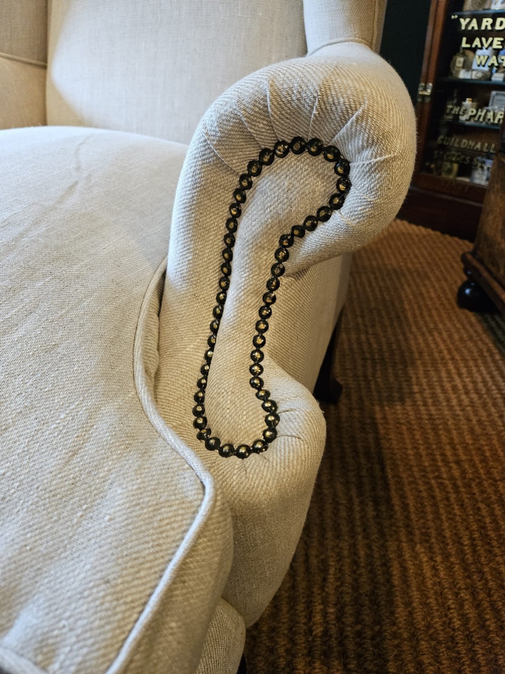 A pair of late Victorian wingback armchairs upholstered in natural oatmeal linen with dark carved cabriole legs and brass stud detailing. View VI