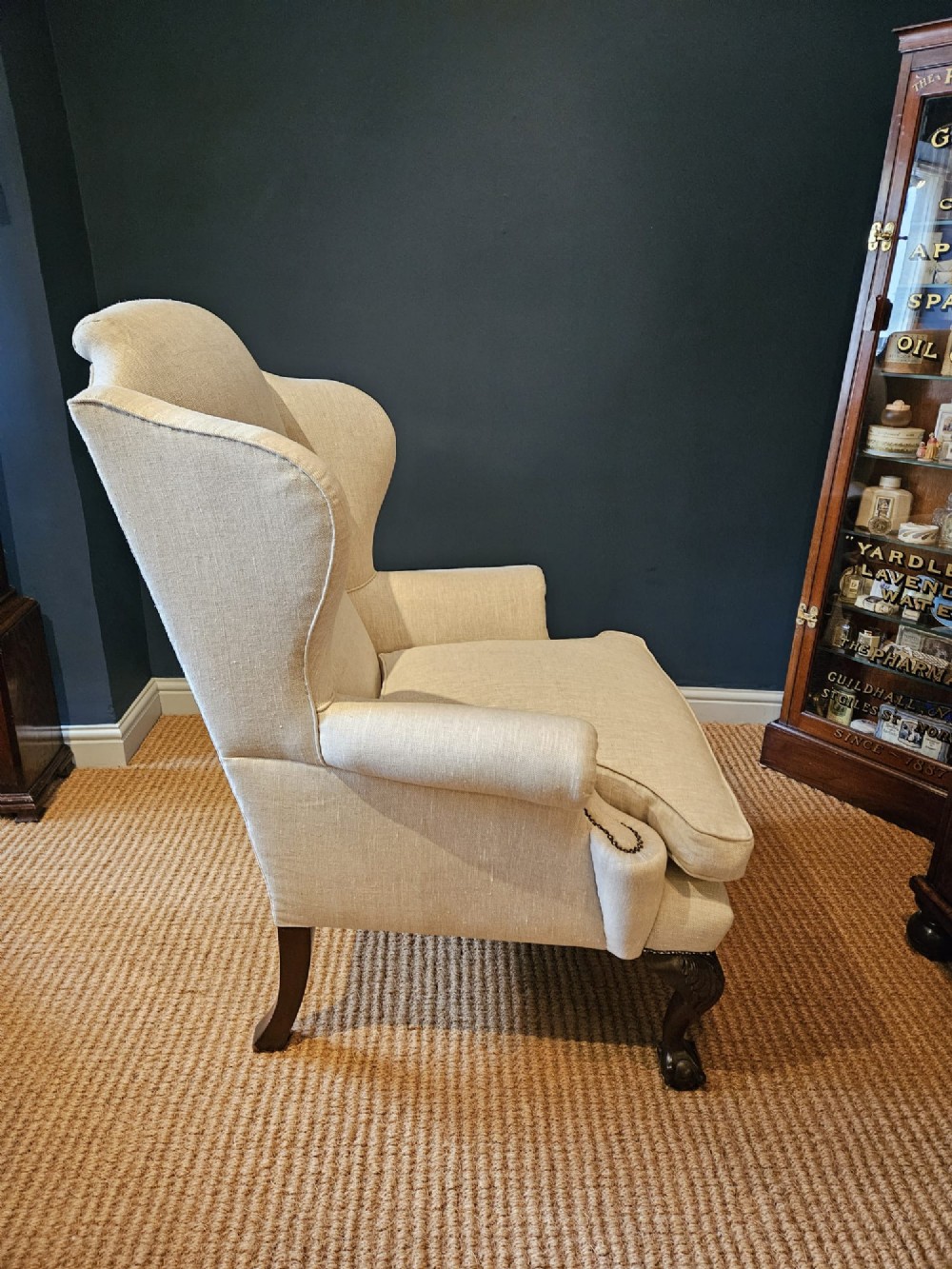 A pair of late Victorian wingback armchairs upholstered in natural oatmeal linen with dark carved cabriole legs and brass stud detailing. View VII
