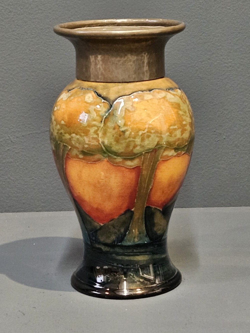 A Moorcroft Eventide glazed earthenware vase featuring a tubelined tree motif against an orange sky with a hammered pewter rim. View III