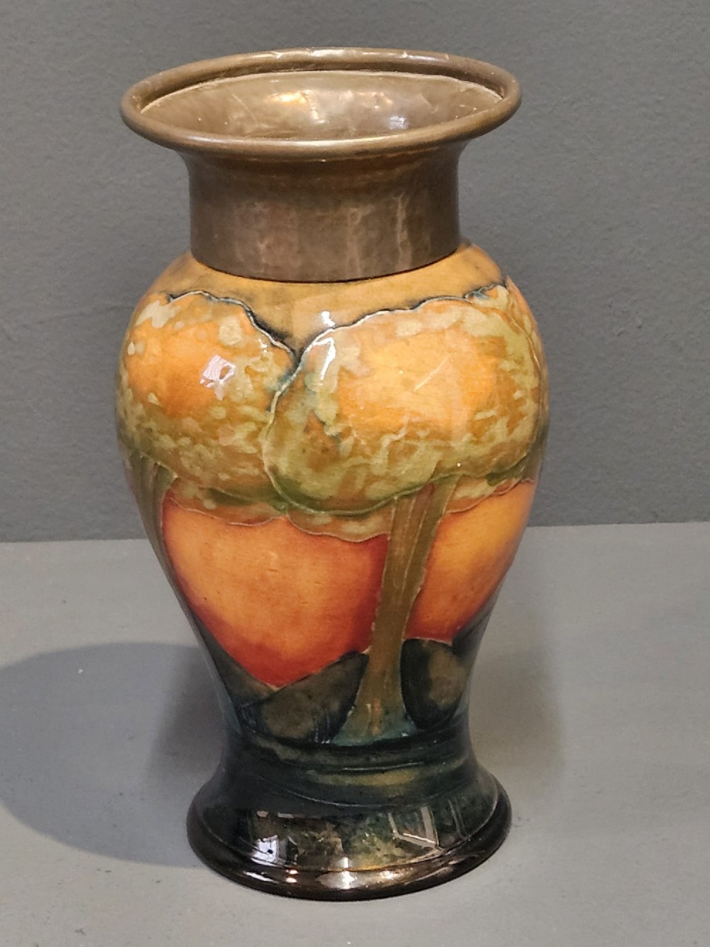 A Moorcroft Eventide glazed earthenware vase featuring a tubelined tree motif against an orange sky with a hammered pewter rim. View IV
