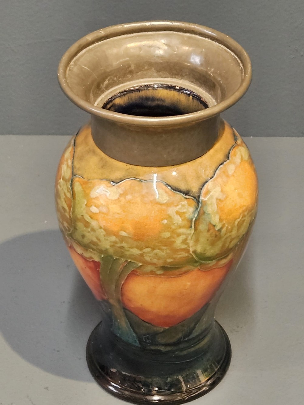 A Moorcroft Eventide glazed earthenware vase featuring a tubelined tree motif against an orange sky with a hammered pewter rim. View VII