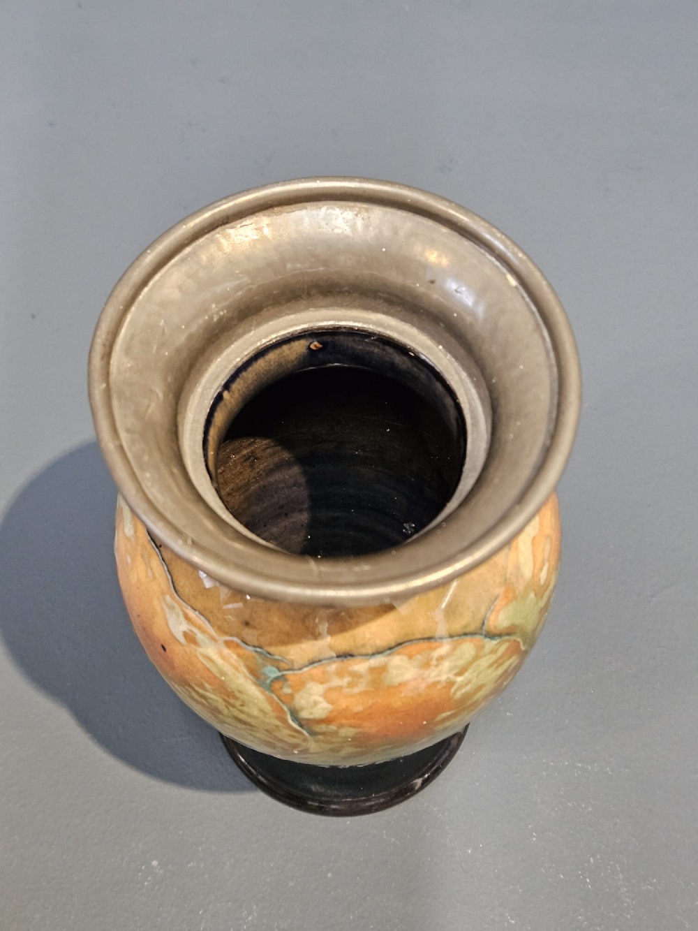 A Moorcroft Eventide glazed earthenware vase featuring a tubelined tree motif against an orange sky with a hammered pewter rim. View VIII