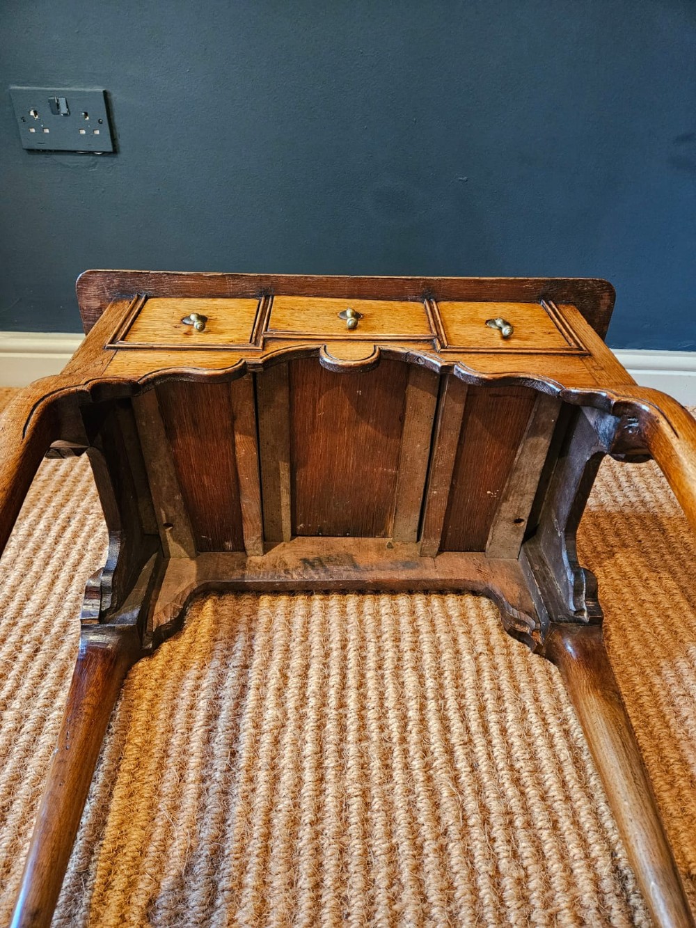 A small George II oak lowboy featuring three drawers with brass teardrop handles, a shaped apron, and cabriole legs terminating in pad feet. View VI