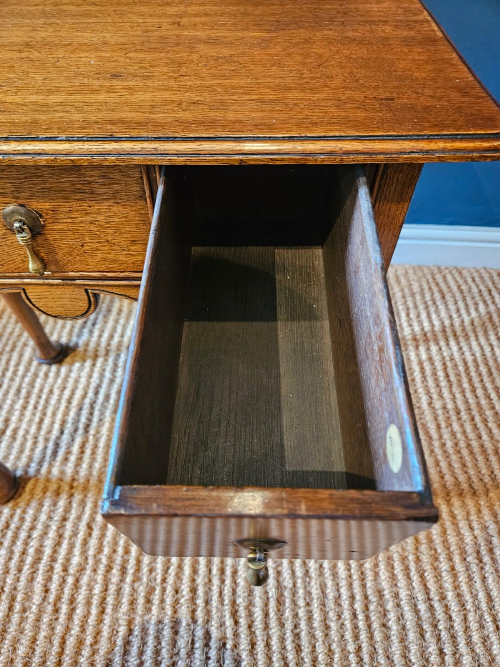 A small George II oak lowboy featuring three drawers with brass teardrop handles, a shaped apron, and cabriole legs terminating in pad feet. View VII
