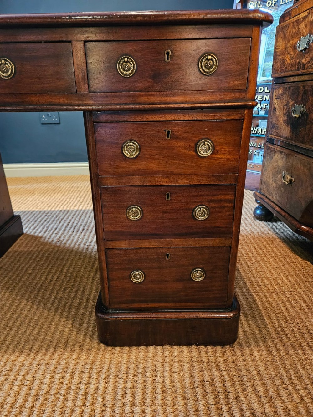 An antique Victorian mahogany pedestal desk with a tan leather writing surface, nine drawers fitted with brass handles, and solid plinth bases. View V
