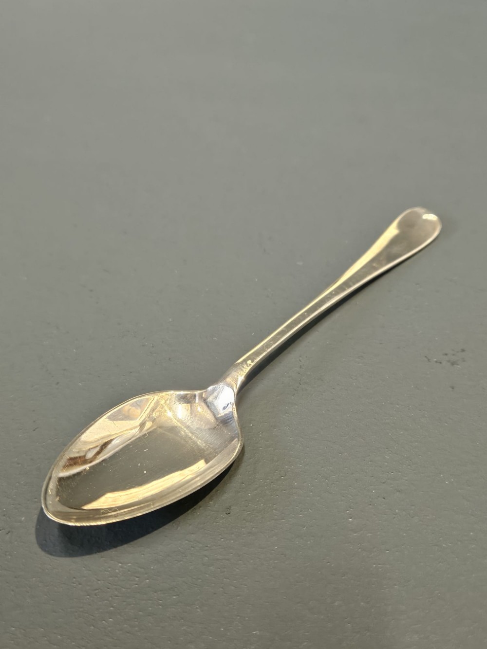 A cased set of twelve sterling silver teaspoons and matching sugar tongs displayed inside a dark blue velvet and cream satin lined box. View II