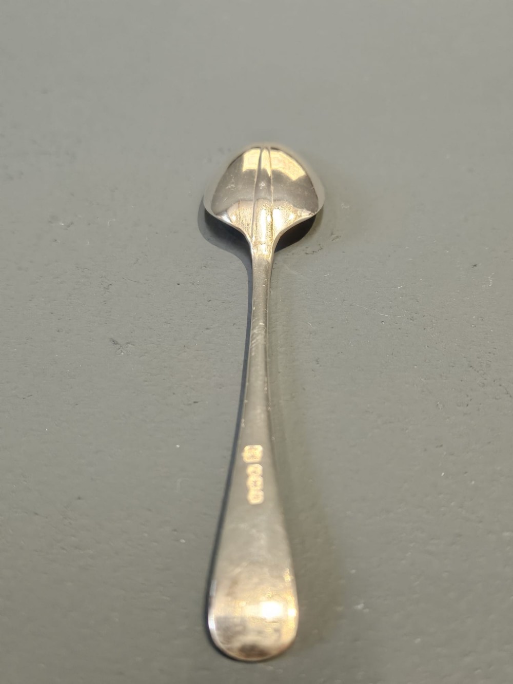 A cased set of twelve sterling silver teaspoons and matching sugar tongs displayed inside a dark blue velvet and cream satin lined box. View IV