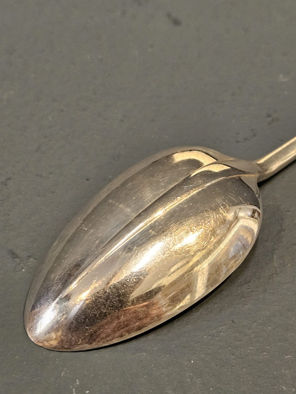 A cased set of twelve sterling silver teaspoons and matching sugar tongs displayed inside a dark blue velvet and cream satin lined box. View V