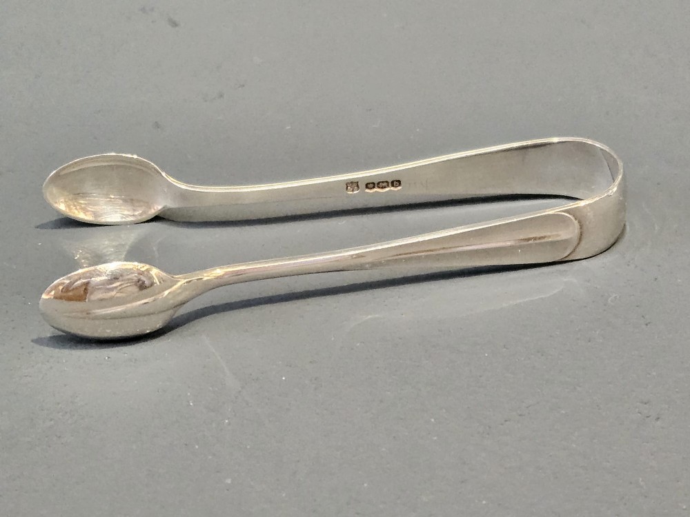 A cased set of twelve sterling silver teaspoons and matching sugar tongs displayed inside a dark blue velvet and cream satin lined box. View VIII