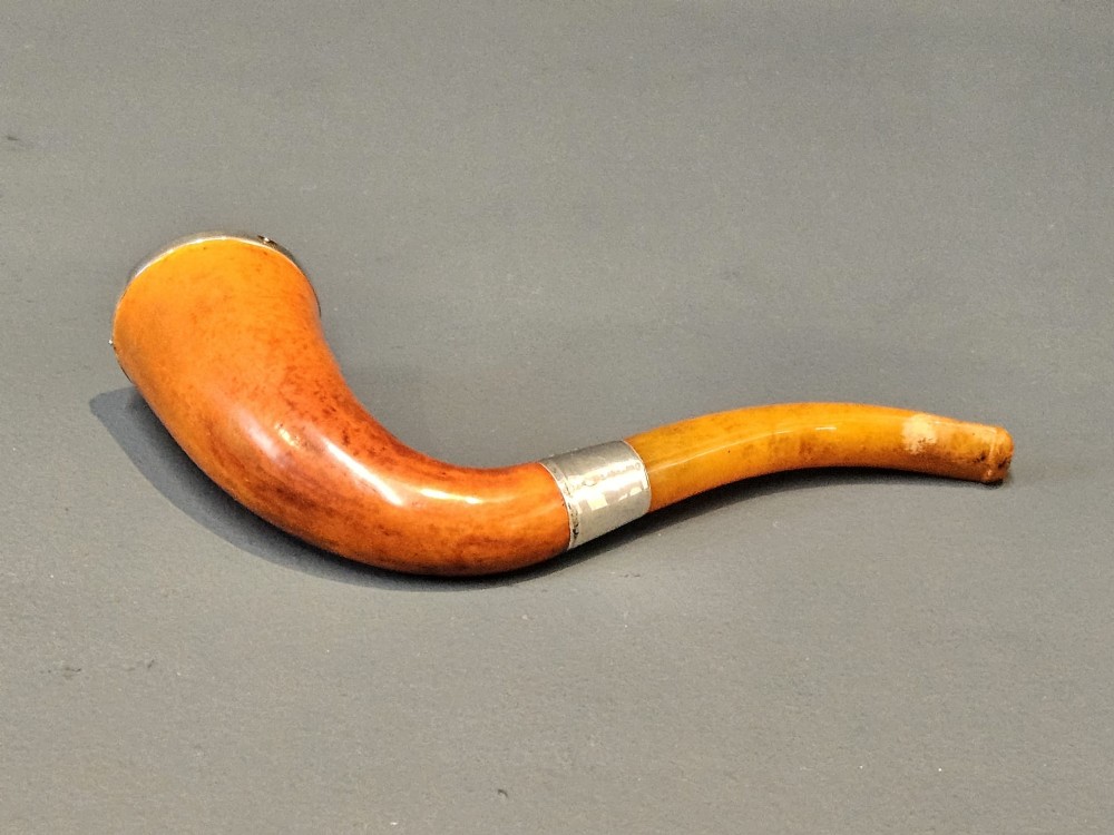 An Edwardian briar wood tobacco pipe featuring a silver band and amber stem resting inside its custom fitted presentation case. View VI