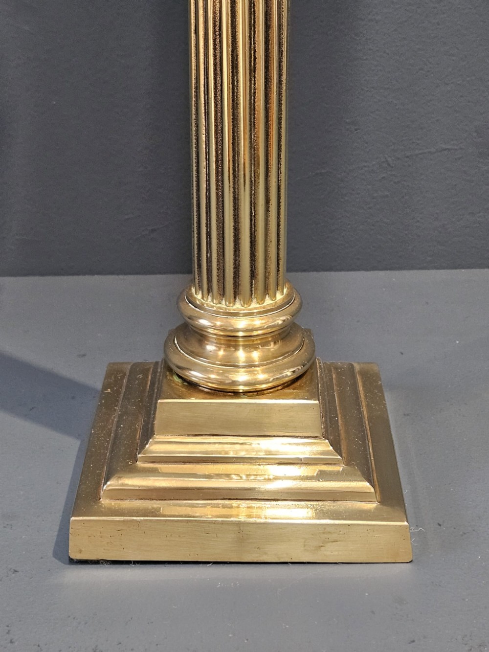 A Victorian brass oil lamp featuring a stepped square base, fluted Corinthian column, cut glass reservoir, and a flared etched cranberry glass shade. View II