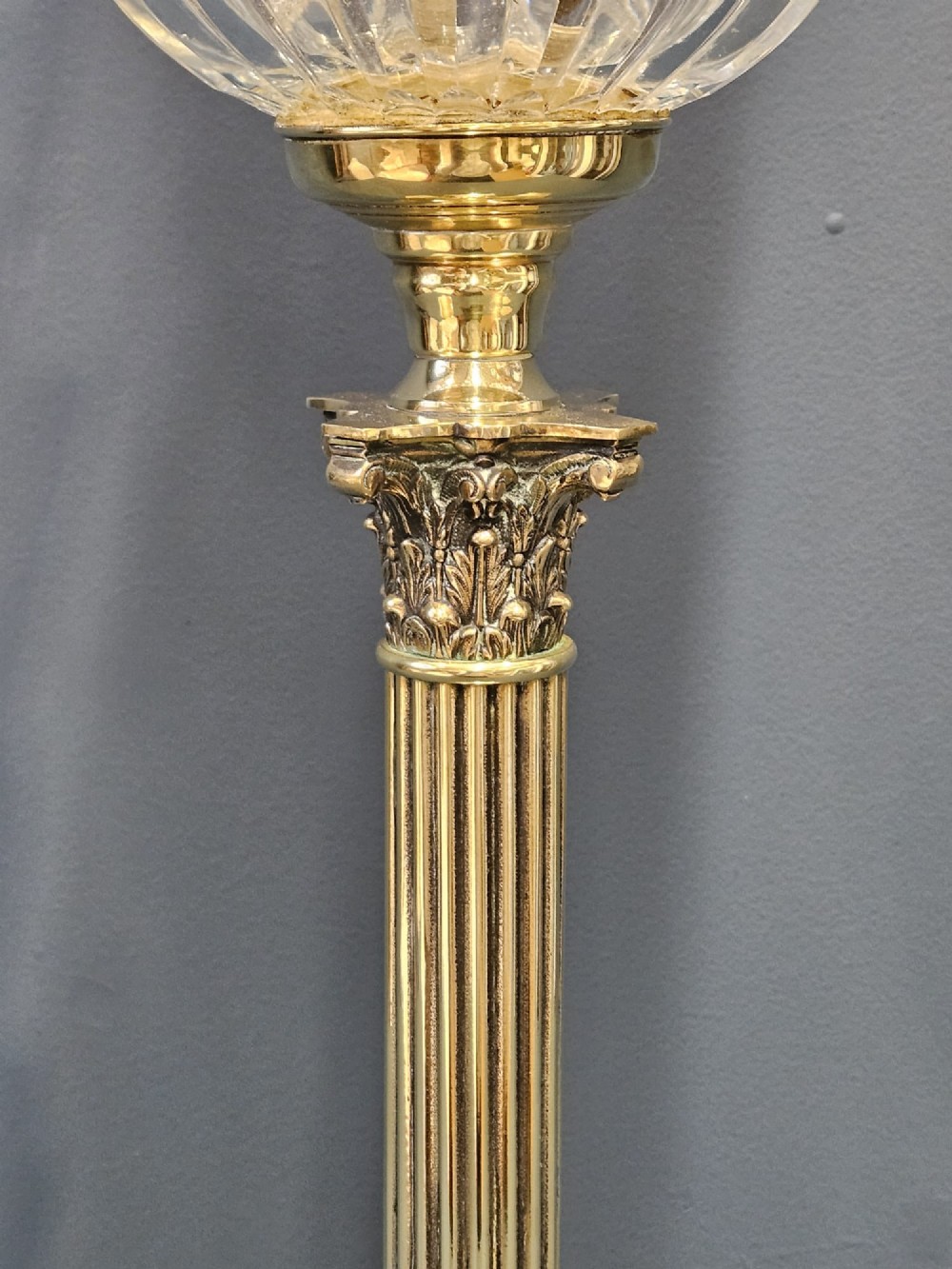 A Victorian brass oil lamp featuring a stepped square base, fluted Corinthian column, cut glass reservoir, and a flared etched cranberry glass shade. View III