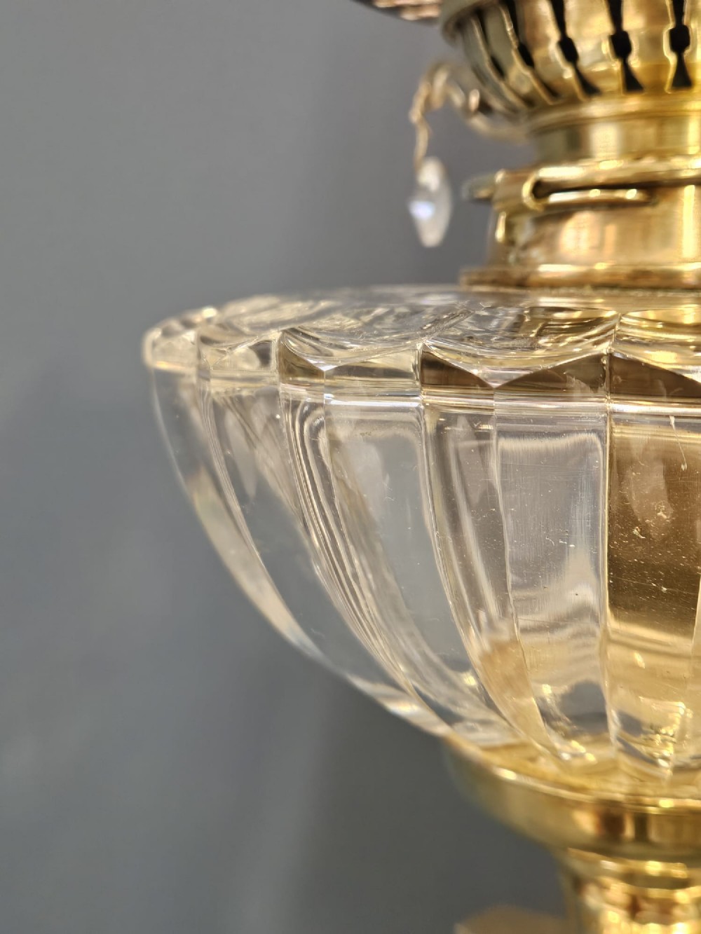 A Victorian brass oil lamp featuring a stepped square base, fluted Corinthian column, cut glass reservoir, and a flared etched cranberry glass shade. View VII