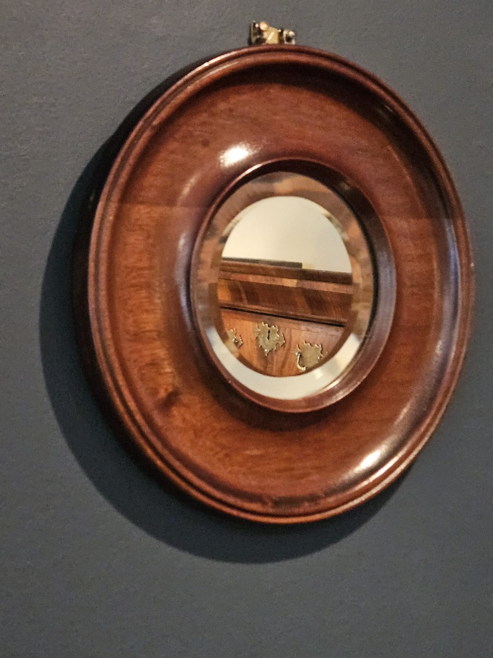 A small Victorian circular mirror featuring a turned mahogany frame with a central bevelled glass plate and top brass hanging loop. View II