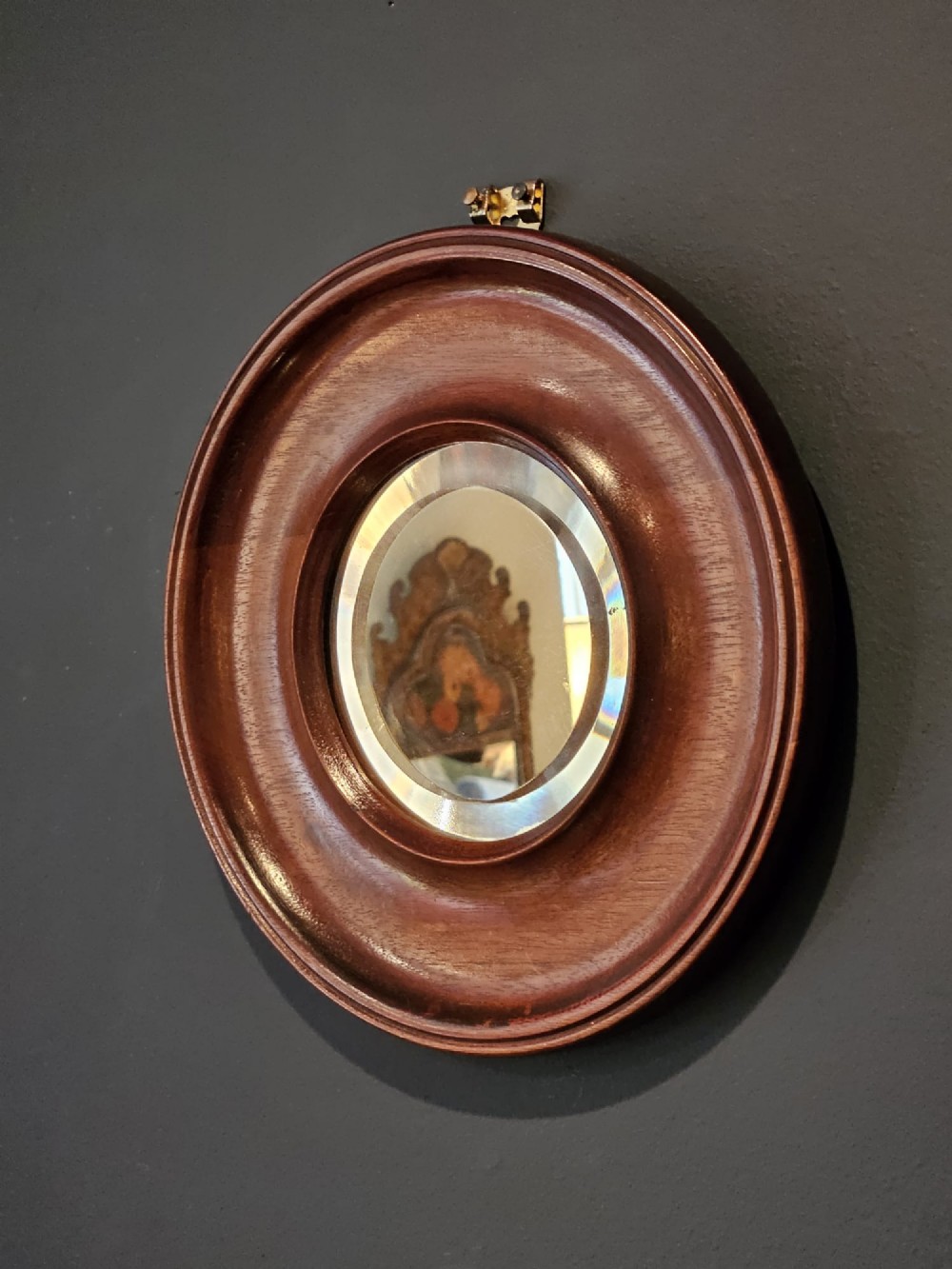 A small Victorian circular mirror featuring a turned mahogany frame with a central bevelled glass plate and top brass hanging loop. View VII