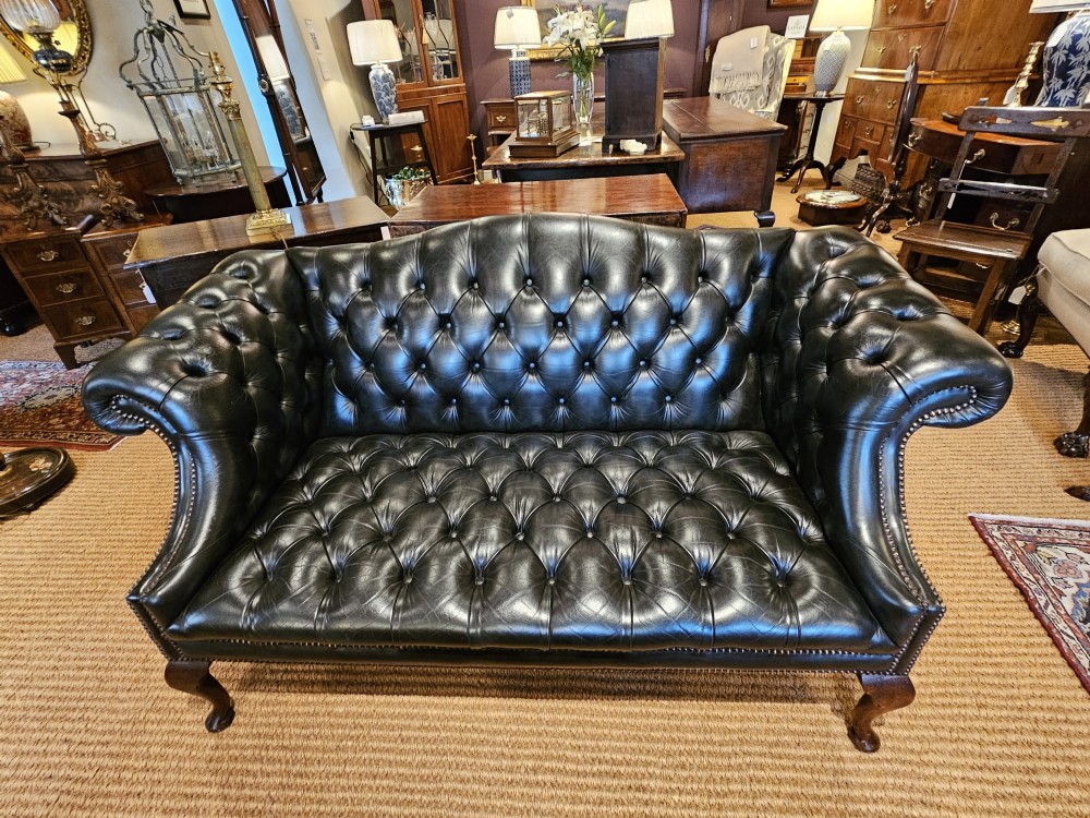 A small bottle green leather Chesterfield sofa featuring deep-buttoned tufting, brass studding along the scrolled arms, and dark wooden legs. View VIII