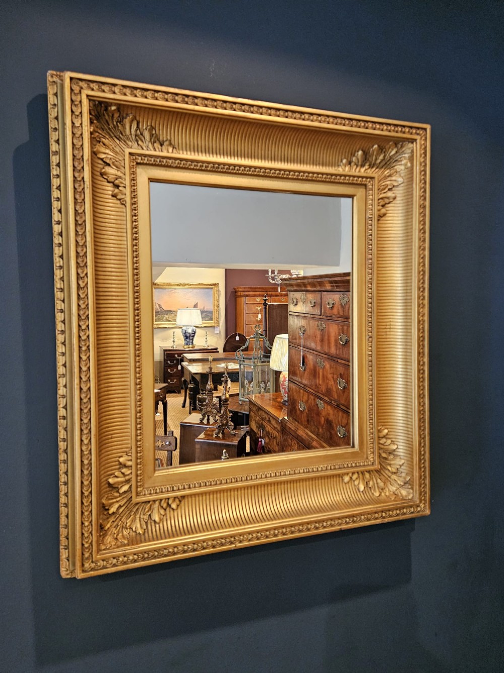 A rectangular Victorian giltwood wall mirror featuring fluted cove moulding, beaded inner borders, and raised acanthus leaf ornamentation at each corner.