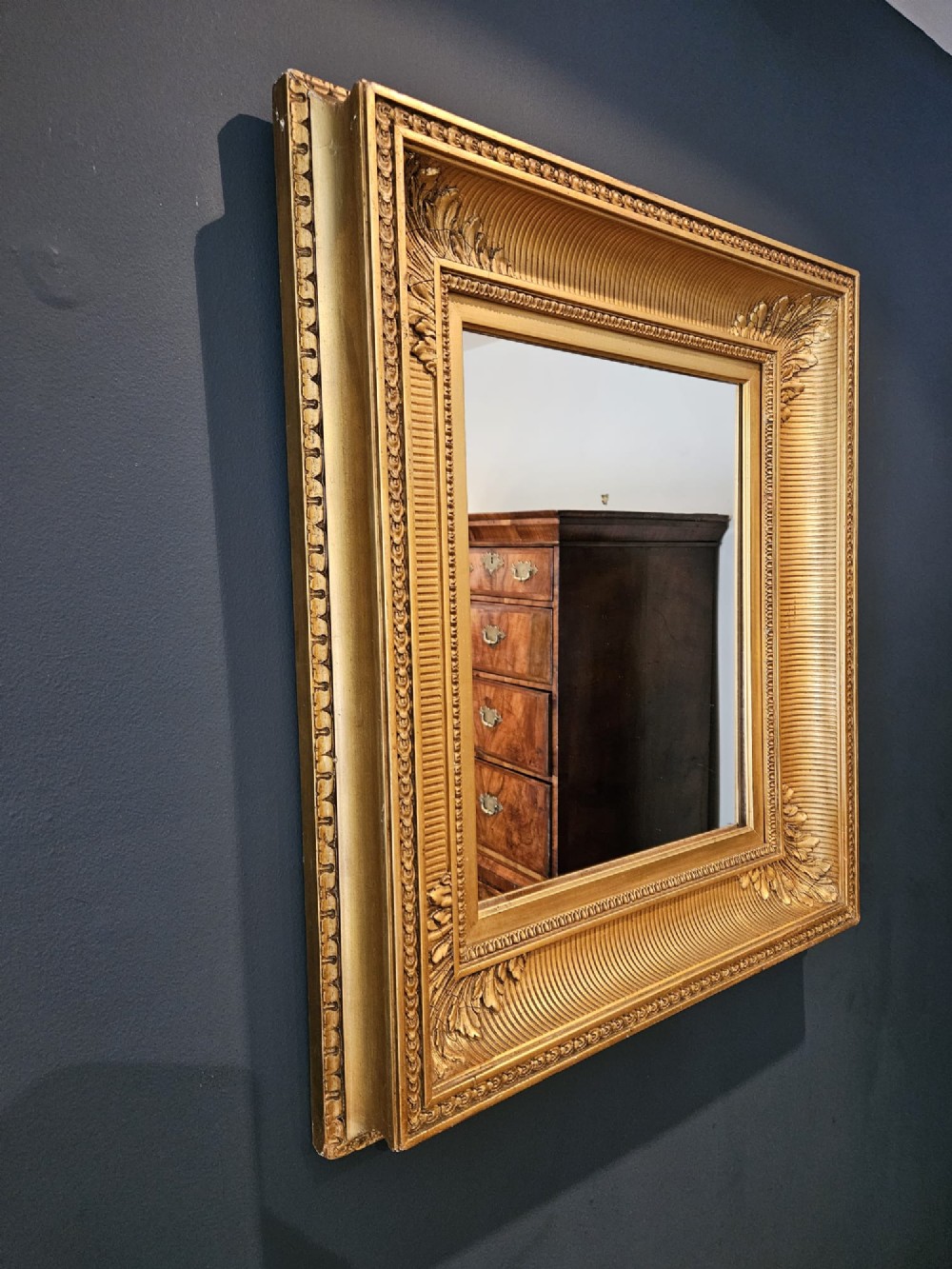 A rectangular Victorian giltwood wall mirror featuring fluted cove moulding, beaded inner borders, and raised acanthus leaf ornamentation at each corner. View VI