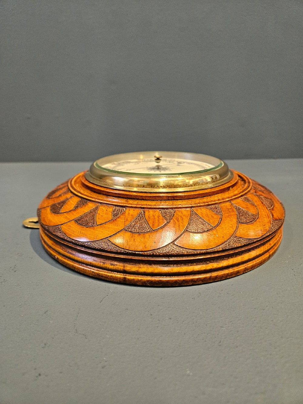 A circular Victorian aneroid wall barometer housed in a turned and carved oak case with a brass bezel. View IV