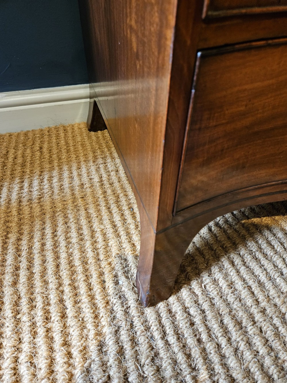 A George III mahogany chest of drawers featuring a curved serpentine front, four graduated drawers with brass swan-neck handles, and splayed feet. View VI