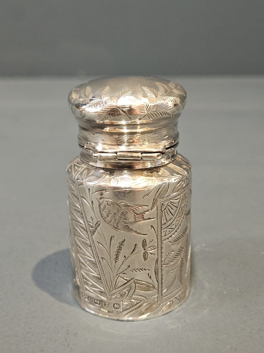 A cylindrical Victorian silver scent bottle featuring engraved artwork of two owls perched on a branch within a circular border. View III