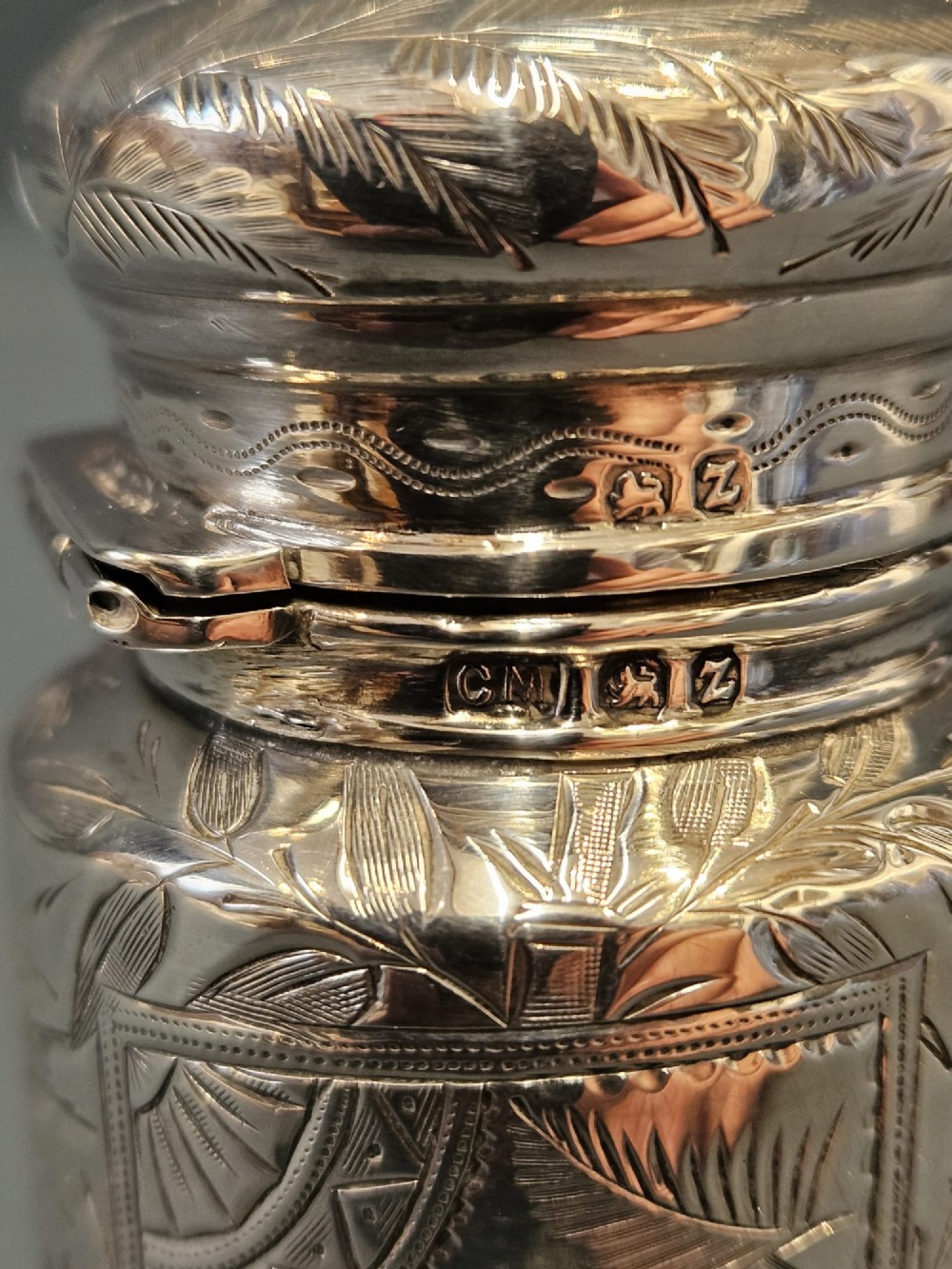 A cylindrical Victorian silver scent bottle featuring engraved artwork of two owls perched on a branch within a circular border. View V
