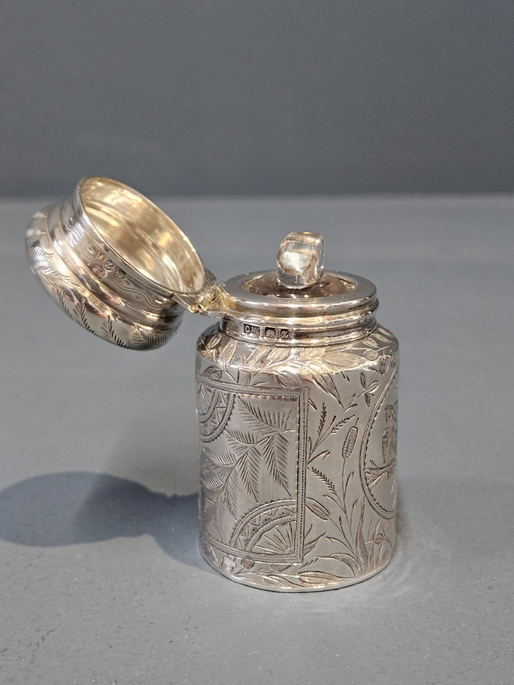 A cylindrical Victorian silver scent bottle featuring engraved artwork of two owls perched on a branch within a circular border. View VII