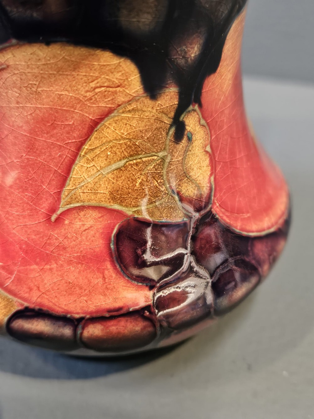 An Art Nouveau Moorcroft earthenware vase with a flared rim, featuring hand-painted tube-lined pomegranates and berries against a deep cobalt blue background. View II
