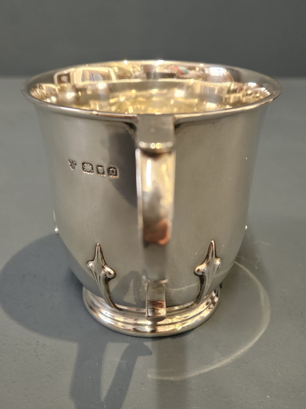 A hallmarked sterling silver mug with raised strapwork details around the lower body, a gilded interior, and a single loop handle. View IV