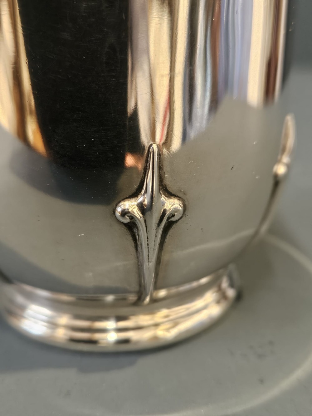 A hallmarked sterling silver mug with raised strapwork details around the lower body, a gilded interior, and a single loop handle. View VIII