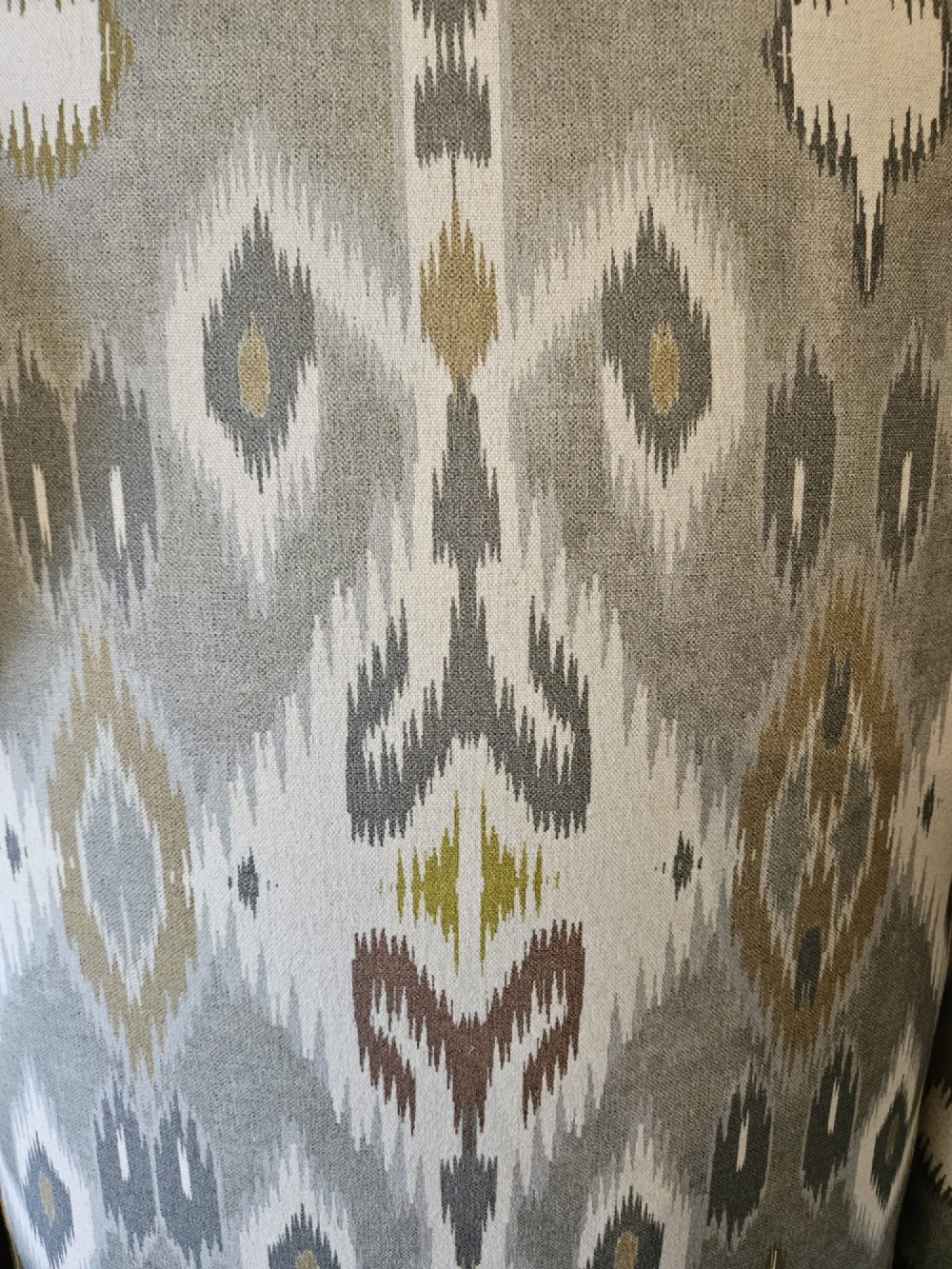 An Edwardian wingback armchair upholstered in a patterned ikat fabric featuring grey and beige tones, supported by carved dark mahogany cabriole front legs. View II