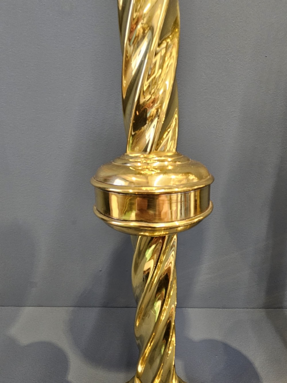 A pair of tall, polished brass Victorian church candlesticks with barley twist stems, crenellated crowns, and circular stepped bases. View II