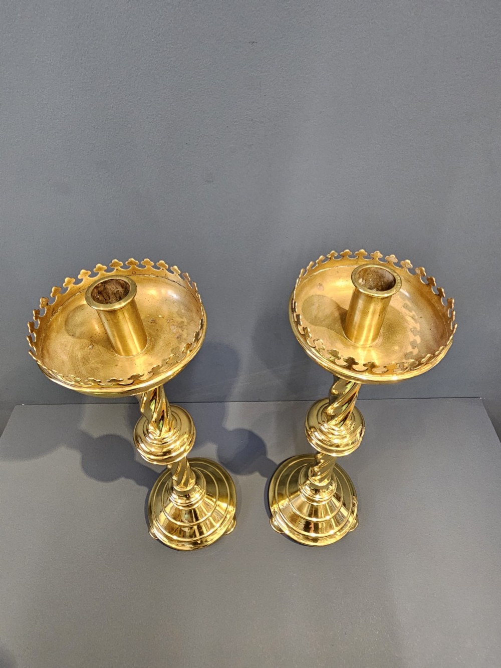 A pair of tall, polished brass Victorian church candlesticks with barley twist stems, crenellated crowns, and circular stepped bases. View VI