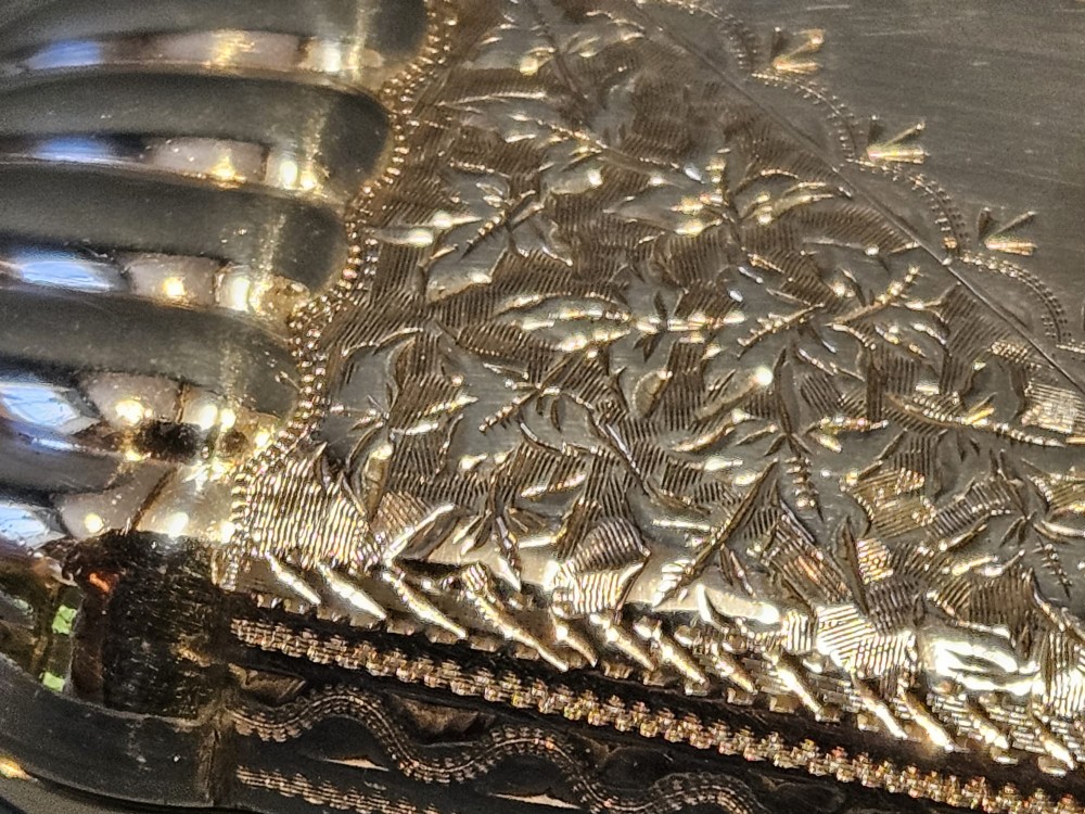 A small rectangular Victorian sterling silver cheroot case featuring hand-engraved foliate decoration and ribbed fluted ends on a grey surface. View IX